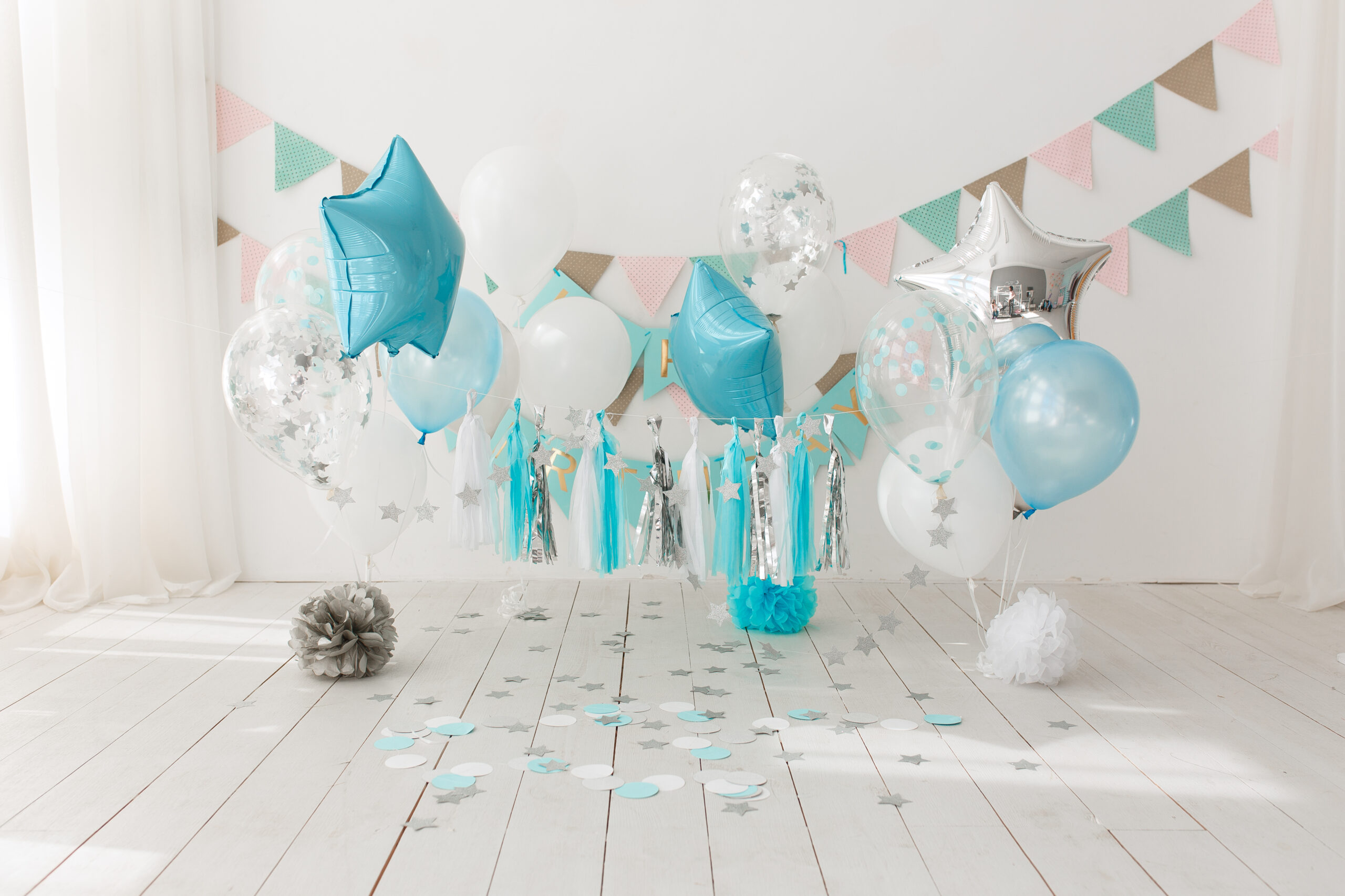 Festive background decoration for birthday celebration with gourmet cake and blue balloons in studio, cake smash first year concept.